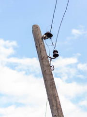 Left-leaning old wooden pole with insulators and electrical wiring