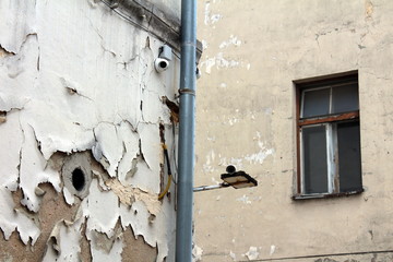 New closed circuit TV CCTV security cameras mounted on corner of old abandoned building with dilapidated cracked facade next to new gutter pipe in old part of town