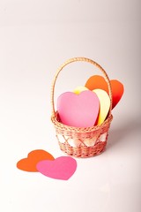 Papier colored hearts in basket on white bacground. Тhe holidays. St. Valentine's Day.