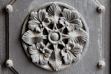 Part of old wooden doors with decorative flower ornament in center surrounded with thick frame texture background wallpaper