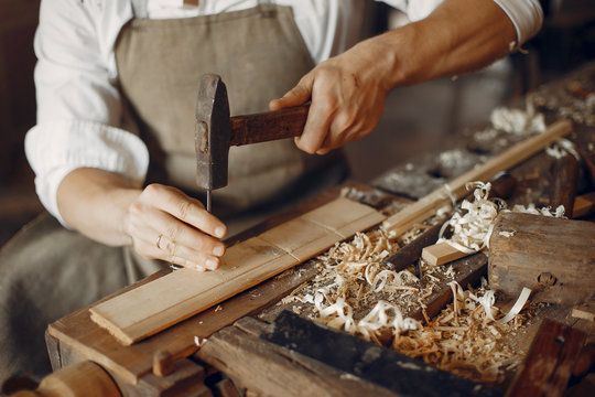Man working with a wood. Carpenter in a white shirt