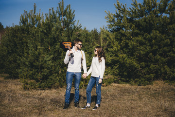 Happy girl and guy with tourist backpack and guitar walking in nature, travel love story concept, selective focus