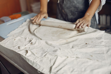 Woman in a pottery. Master make a dishes. Artist works with a clay