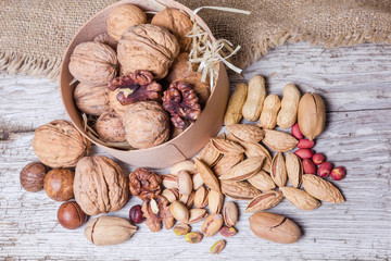 Various nuts on old wooden planks with burlap, top view