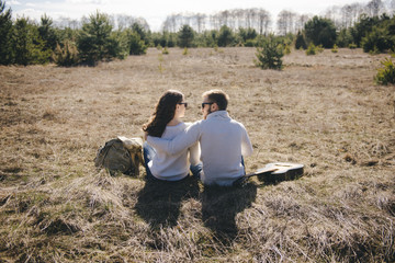 Happy girl and guy with tourist backpack and guitar walking in nature, travel love story concept, selective focus