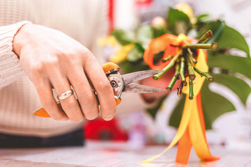 Woman florist pruning rose on bouquet in flowers shop