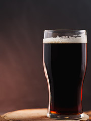 A glass of strong brown Belgian ale on a dark background