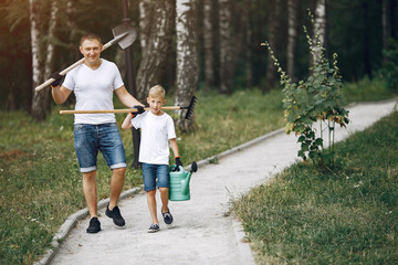 Family on a yard. Father with son with green funnel and shovel