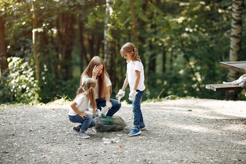 Obraz premium Volunteers collects rubbish. Children in a park. Kids in a white t-shirts