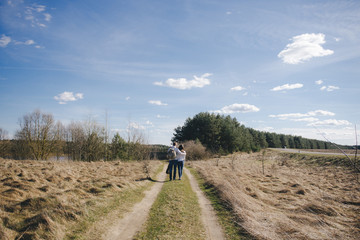 Happy girl and guy with tourist backpack and guitar walking in nature, travel love story concept, selective focus