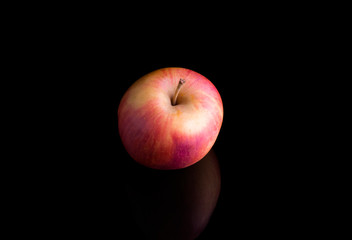 pink juicy Apple on a black background with reflection