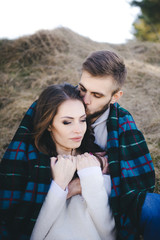 Happy girl and guy sitting in a field covered with a blanket, travel concept love story