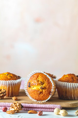Vanilla caramel muffins in paper cups on white wooden background. Delicious cupcake with raisins, almonds and nuts. Homemade biscuit cakes. Copy space for text..