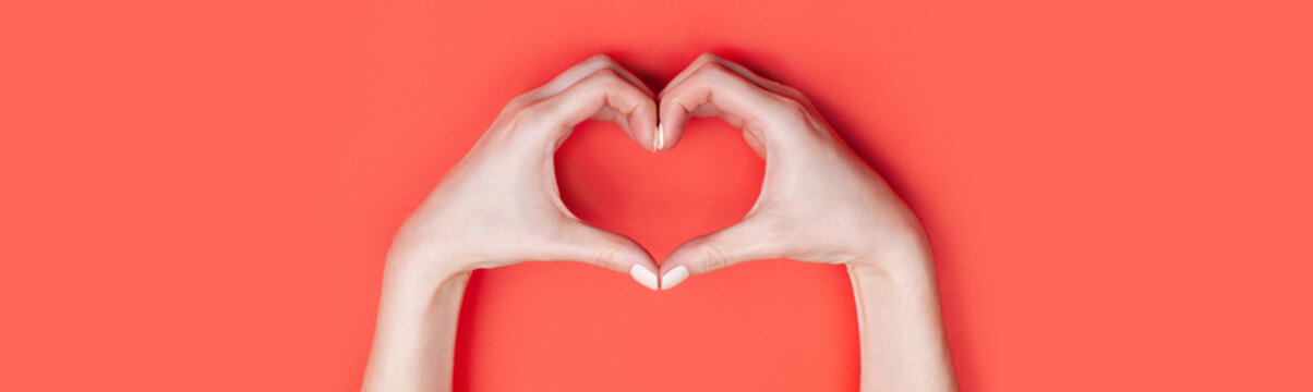 Female hands show a heart symbol on a red background. Place for text, copy space, banner format