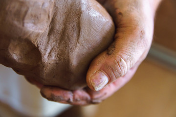 Male hand holds piece of clay.