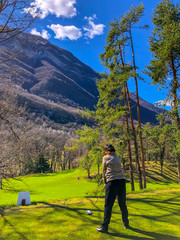Fototapeta premium Golfer Teeing Off with Driver and with Mountain View in Italy.