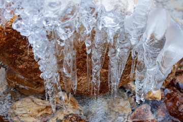 bizarre white winter icicles on river stone