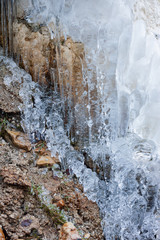 bizarre white winter icicles on river stone