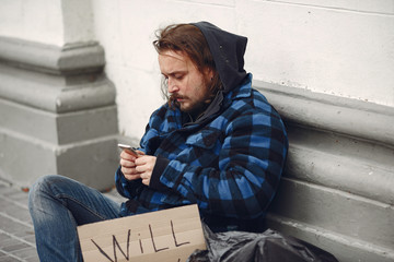 Homeless in a city. Man asking for food. Man with a tablet