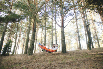 Obraz na płótnie Canvas Couple in love, girl and guy in hammock enjoys in the woods, travel love story concept