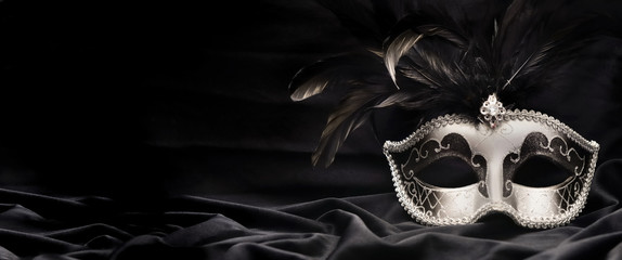 beautiful venitian carnival mask with feather on dark fabric background in panoramic size - obrazy, fototapety, plakaty
