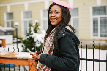Cute black woman have fun in a city. Beautiful black girl in a pink beret. Stylish lady with phone