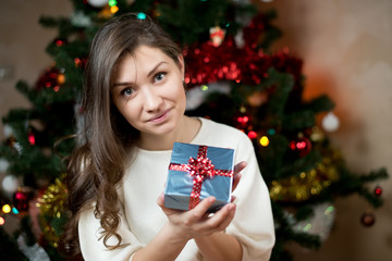 young woman with a gift in hands on a background of the Christmas tree