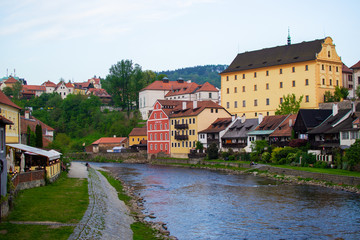 Fototapeta na wymiar View of traditional czech houses and Vltava river with green trees and vegetation, in Cesky Krumlov, Czech Republic