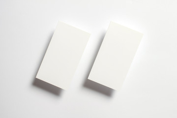 Two white blank textured business cards flying and isolated on white paper background, us standard size 3.5 x 2 inches, real non professional studio photo.