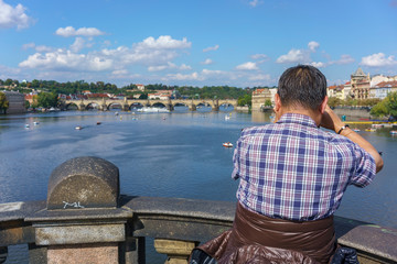 Fototapeta premium Male tourist taking picture of beautiful cityscape of Prague in summer , Czech Republic