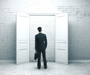 Businessman with briefcase standing in brick room.