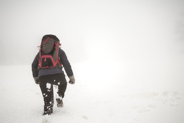 Fototapeta na wymiar Mountaineer girl walking through the snow on her back