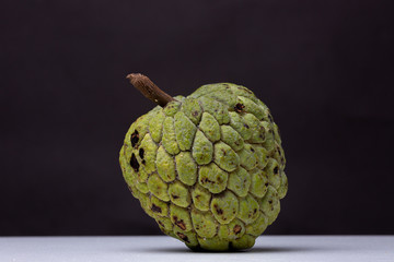Sugar-apple or 'Fruta de Conde' [Earl Fruit] as the fruit is known in Brazil with its typical scales on a white surface with dark background