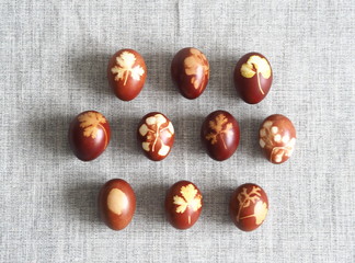 A collection of Easter eggs stained with onion husks with imprints of fresh leaves, on a fabric background. Creative design. Easter folk traditions. We meet Easter Sunday.