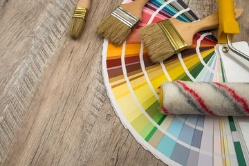 Color palette guide and paint brush roller  on wood board.