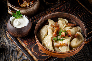 Ukrainian cuisine. vareniki with potatoes and fried pork fat - cracklings. Serving dishes in a Ukrainian style restaurant with sour cream on a wooden background. background image, copy space text