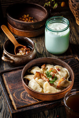 Ukrainian cuisine. vareniki with potatoes and fried pork fat - cracklings. Serving dishes in a Ukrainian style restaurant with sour cream on a wooden background. background image, copy space text