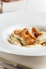 Ukrainian cuisine. vareniki with potatoes and fried pork fat - cracklings. Serving dishes in a restaurant in a white plate with sour cream. background image, copy space text