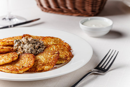 Ukrainian cuisine. A grated potato dish of deruny, draniki grated on a white plate with red wine. Serving dishes in a restaurant in a white plate. background image, copy space text