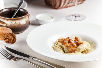 Ukrainian cuisine. vareniki with potatoes and fried pork fat - cracklings. Serving dishes in a restaurant in a white plate with sour cream. background image, copy space text