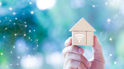 Smart home concept with hand holding a wooden block house and wireless connections icons, Smart house technology