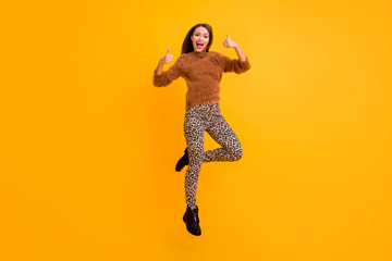 I like it. Full length photo of pretty lady jumping up high raising thumbs up approving friend youth trend look wear fluffy sweater leopard pants isolated yellow color background