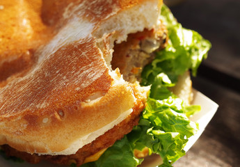 Close-up of vegan burger on a sesame seed bun with fresh salad and veggies.