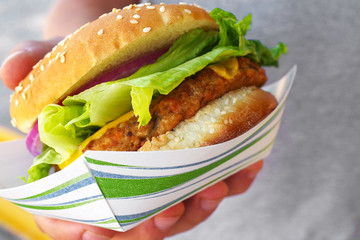 Close-up of vegan burger on a sesame seed bun with fresh salad and veggies.