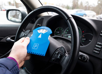 Parking clock in a man's hand. Interior of the car