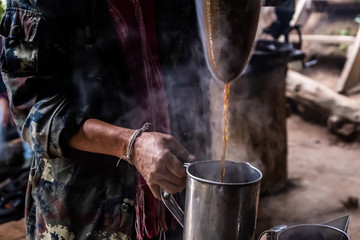 The man pour hot coffee into coffee cup, hands are making ancient Thai coffee.