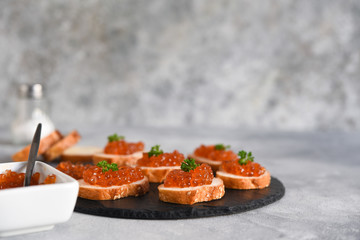 Toast bread with red caviar. Sandwich with caviar and butter on a concrete background.