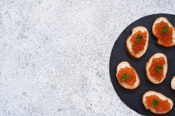 Toast bread with red caviar. Sandwich with caviar and butter on a concrete background.