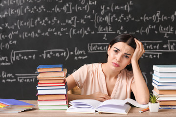 Tired female teacher at table in classroom