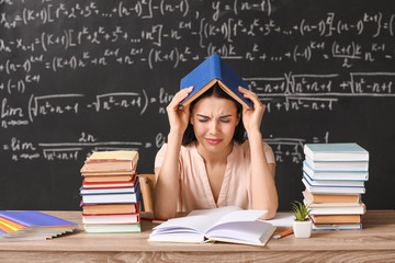 Tired female teacher at table in classroom